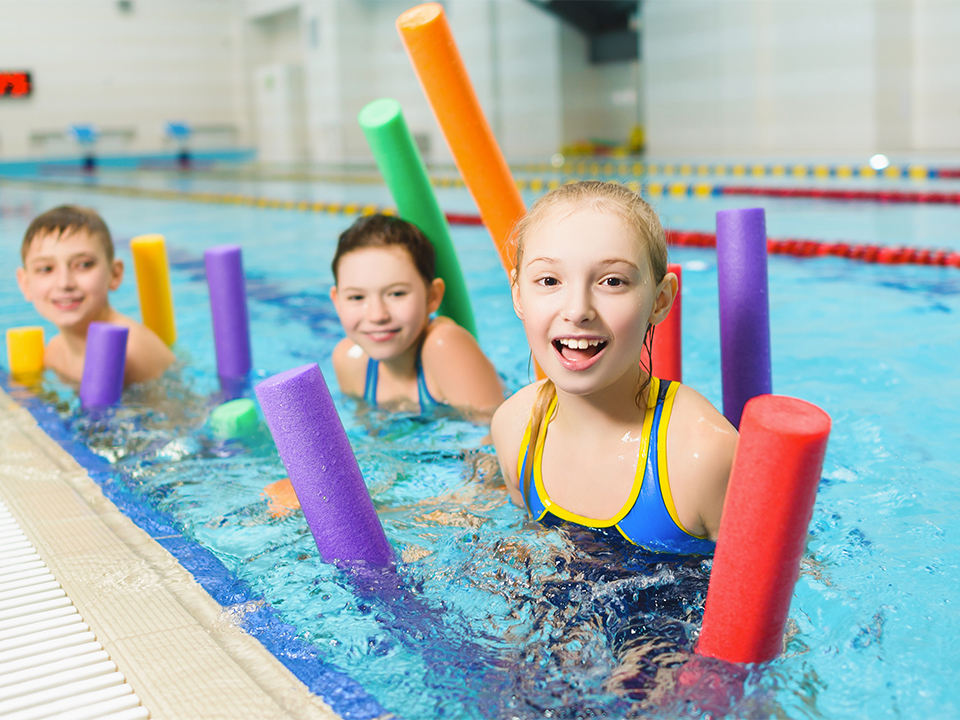 Happy and smiling group of children learning to swim with